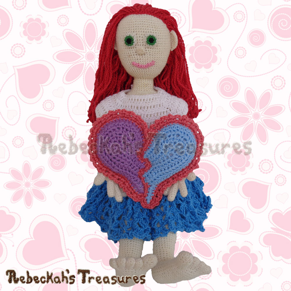 Dolly holding her new pillow! | Dolly's Broken Heart Pillow Story | A Crochet Pattern by @beckastreasures for @getstuffed | Is it an amigurumi or an appliqué? Will it be a necklace, a fob or a pillow? Are the hearts separated to share with your besties or kept whole to show broken hearts can be mended? YOU get to decide!!! | #crochet #pattern #brokenheart #valentine #heart #amigurumi #appliqué #necklace #fob #pillow